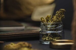 Older adult reviews cannabis packaging beside a medication organizer at a kitchen table.